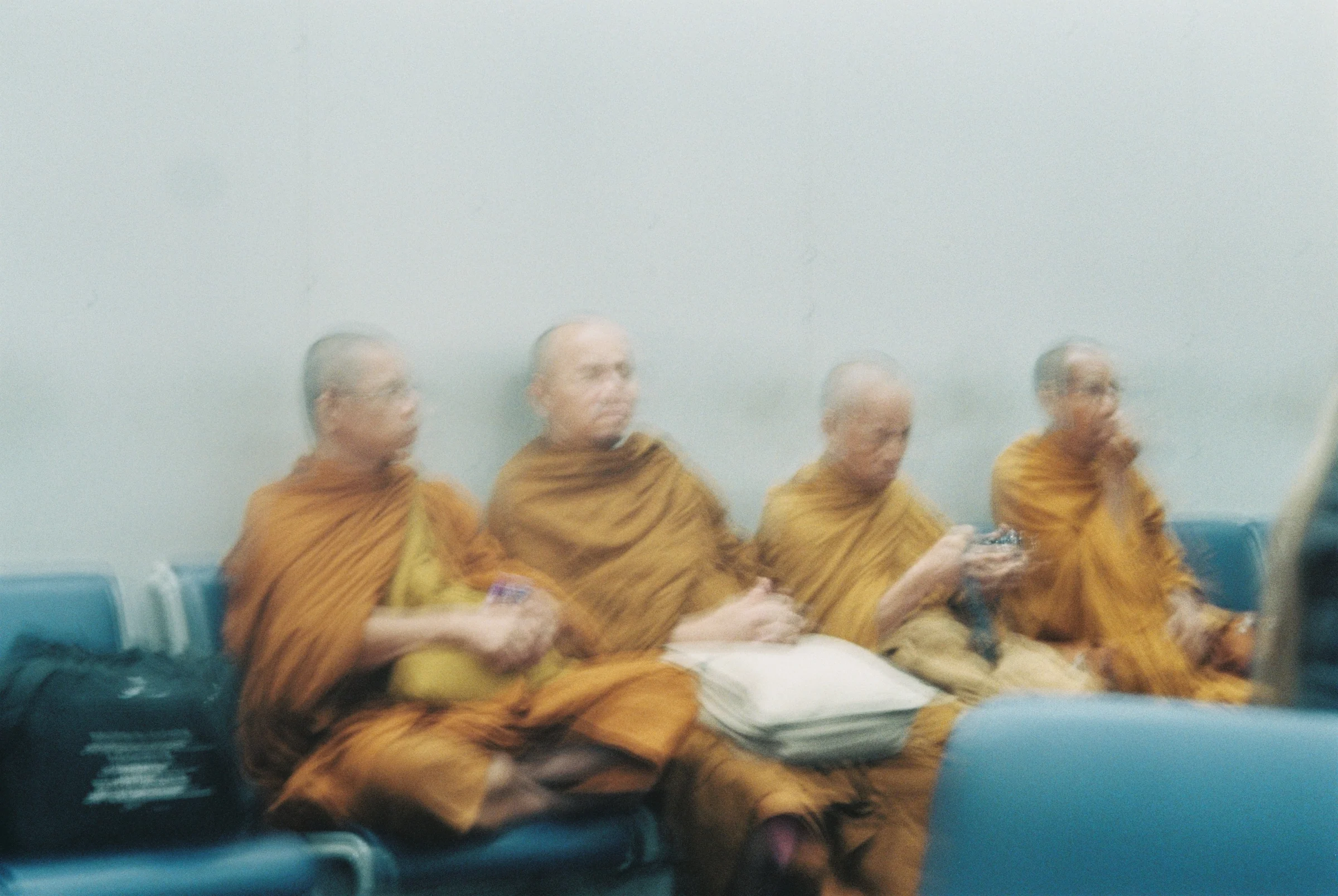 Buddhist monks seated together in a soft-focus film portrait in Thailand.
