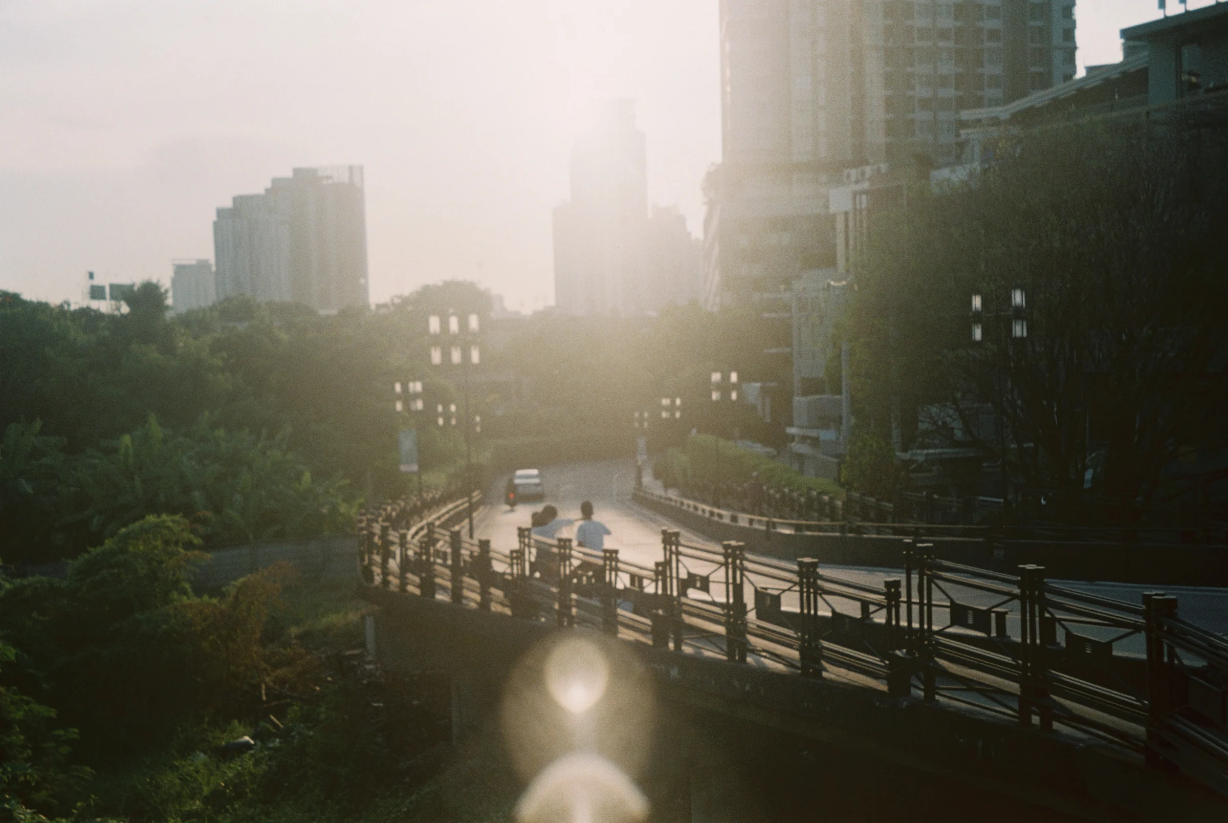 A hazy city overpass and skyline at sunset in Thailand.