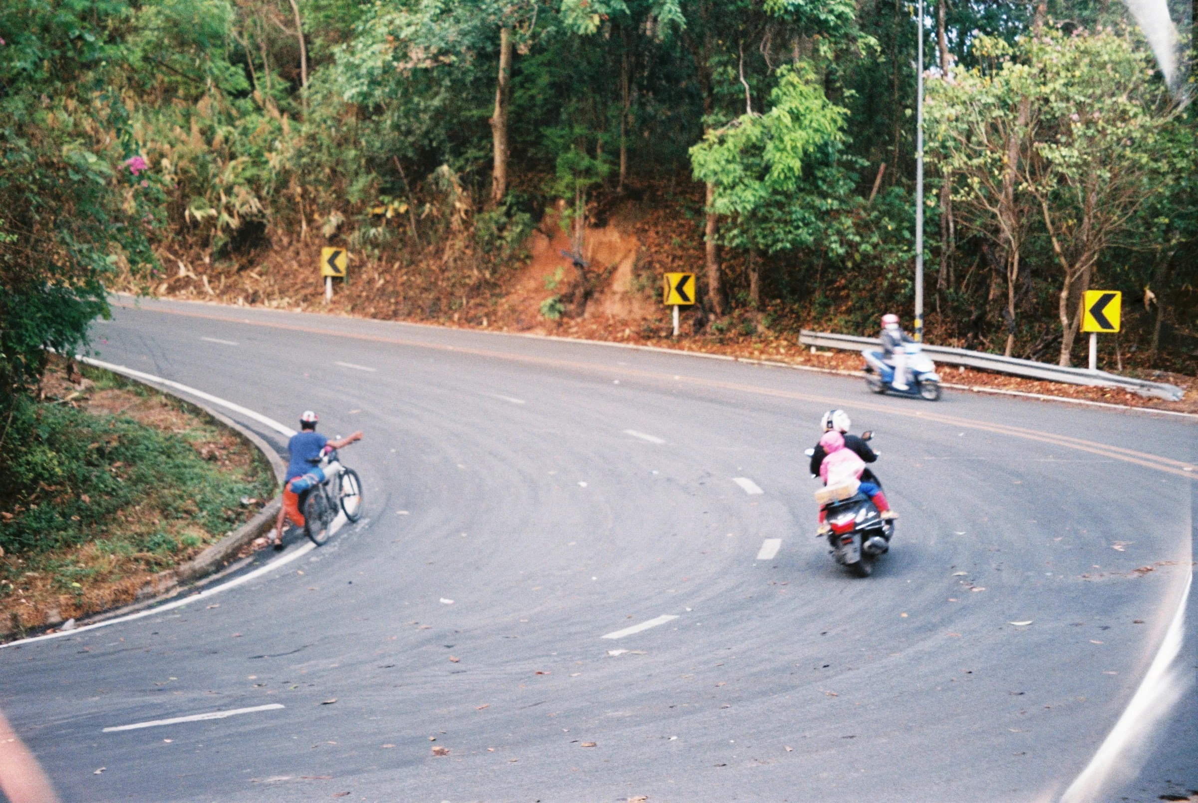 Motorbikes rounding a mountain road curve in Thailand.
