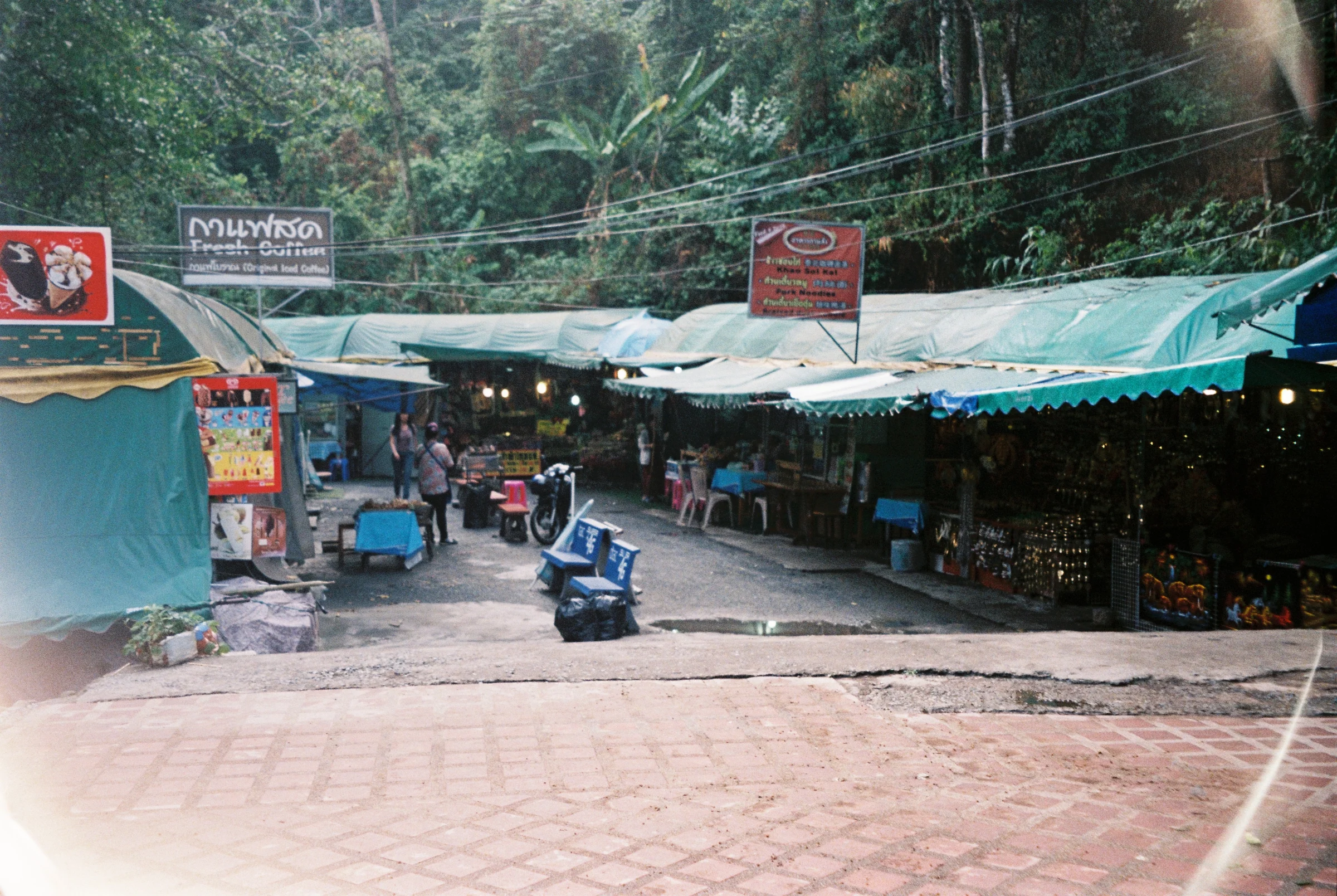 A small roadside market at the edge of a forest road in Thailand.