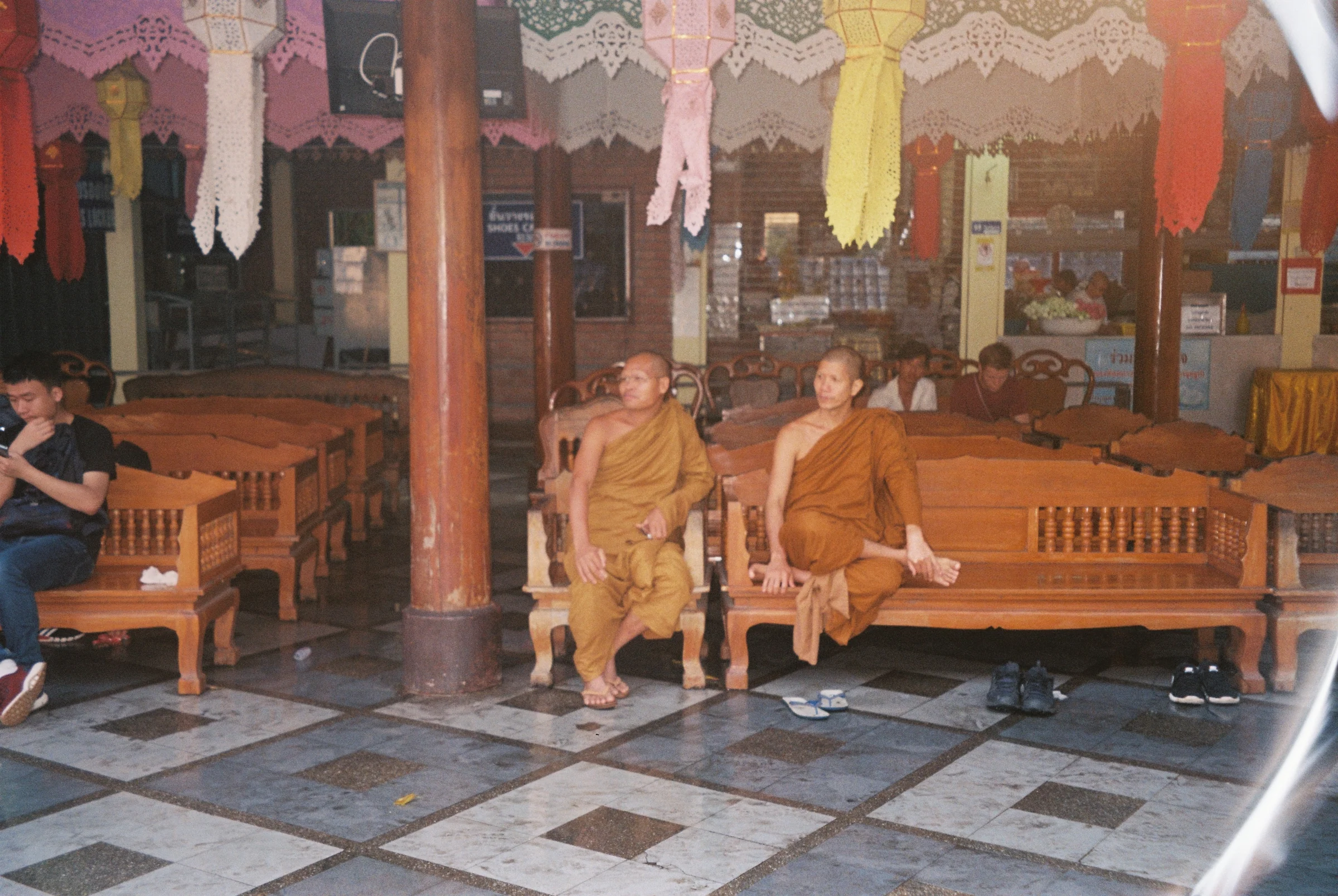 People sitting inside a Thai temple interior.
